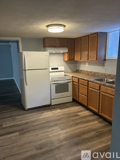 A kitchen with a white refrigerator and wooden cabinets.