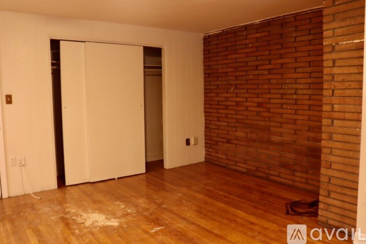 A room with a wooden floor and a brick wall.