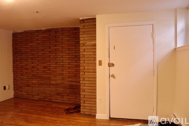 A room with a white door and a brick wall.
