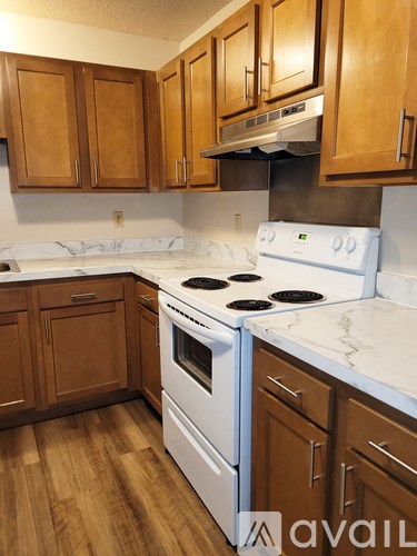 A kitchen with wooden cabinets and a white stove top oven.