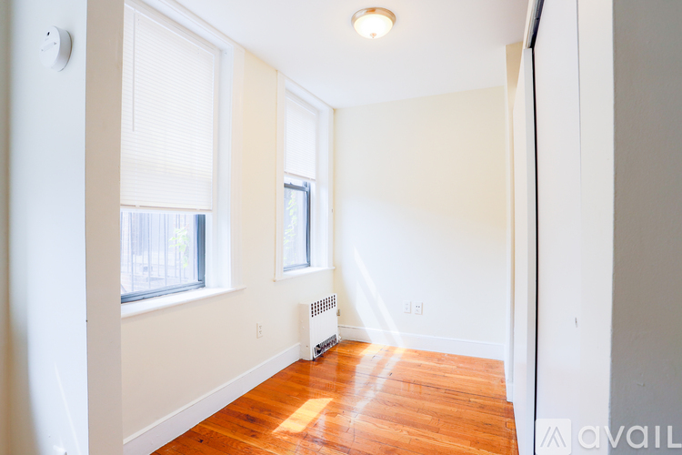A room with a wood floor and a window with blinds.