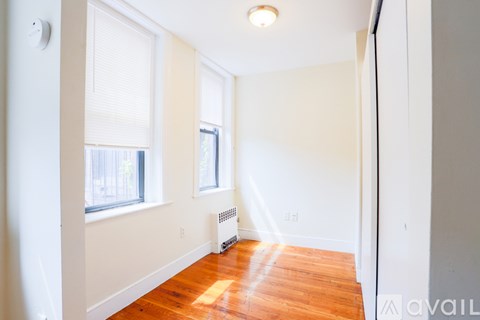 A room with a wood floor and a window with blinds.