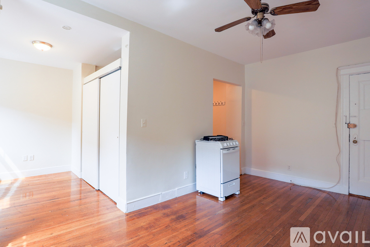 A room with a white fridge and a ceiling fan.