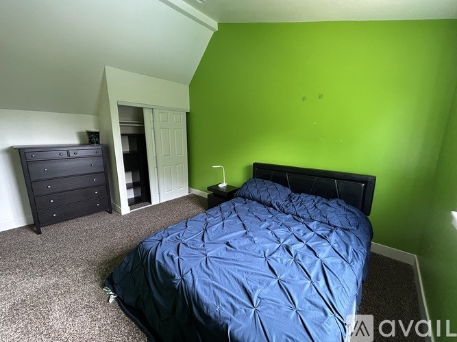 A bedroom with a bed, dresser, and wardrobe.