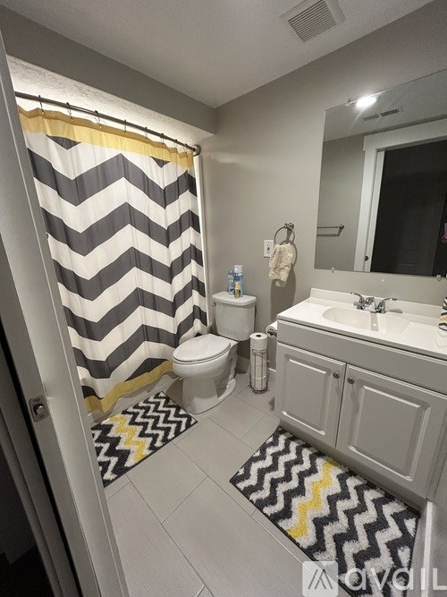 A bathroom with a chevron patterned rug on the floor.