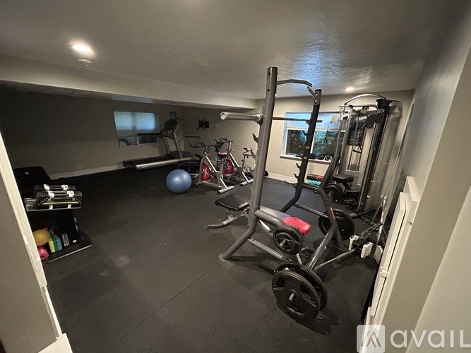A home gym with a variety of equipment including a treadmill, weights, and a bench press.