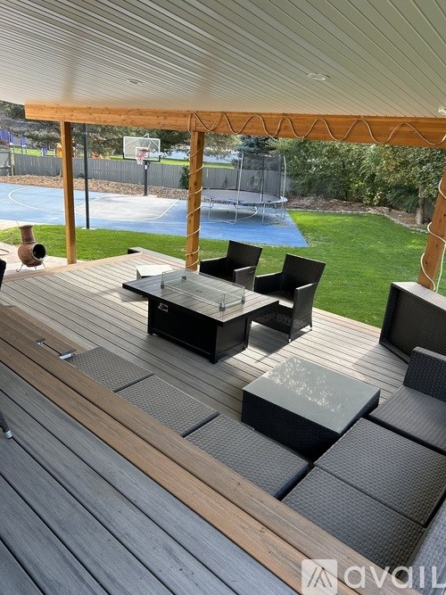 A wooden deck with a table and chairs overlooking a basketball court.