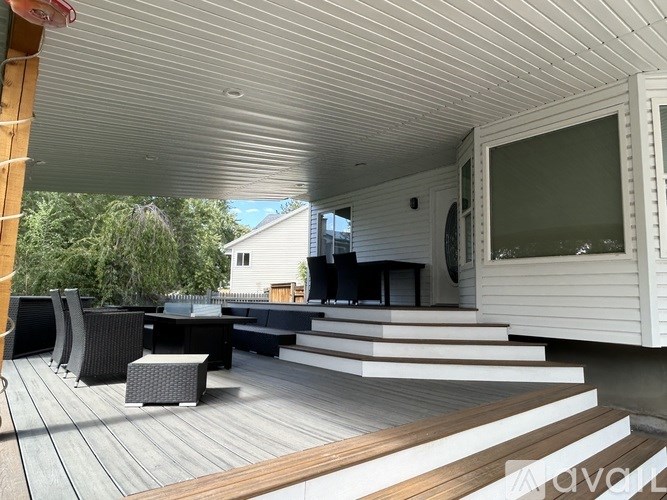 A white outdoor patio with a white sofa and black chairs.