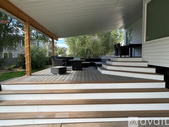 A wooden deck with a bench and steps leading to a house.