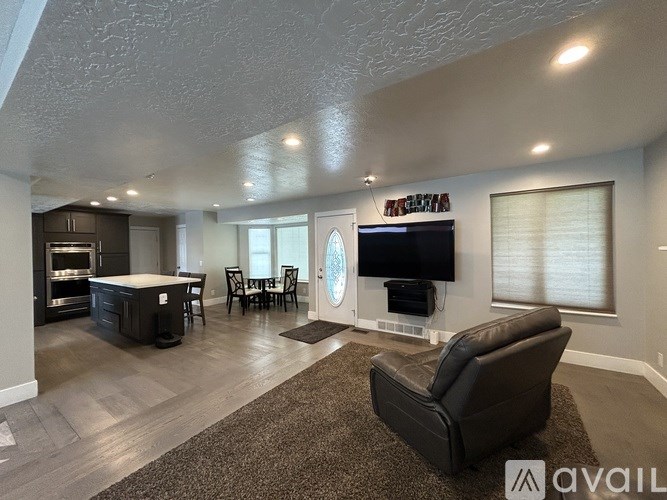 A living room with a black leather chair and a flat screen TV mounted on the wall.