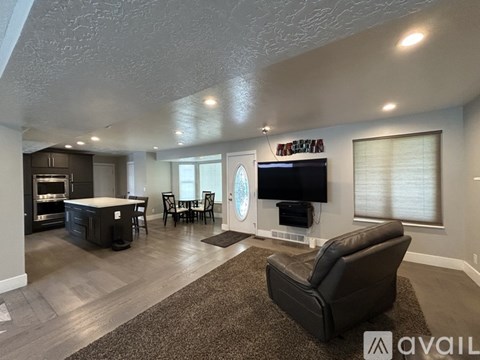 A living room with a black leather chair and a flat screen TV mounted on the wall.