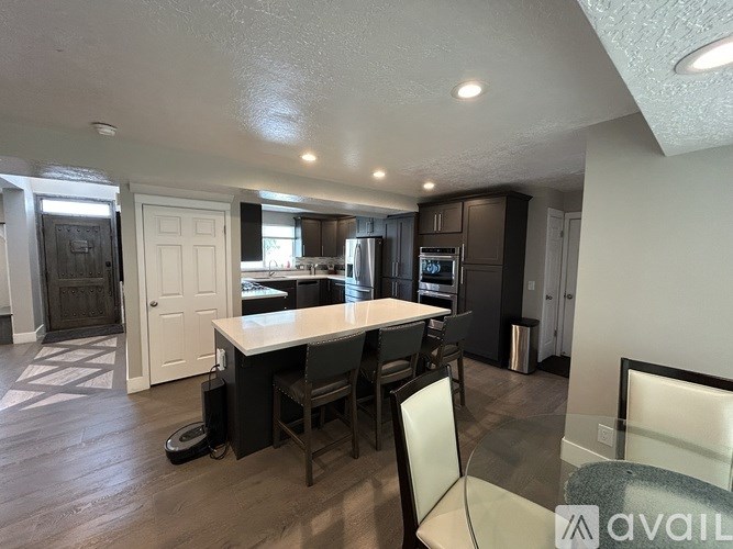 A kitchen with a table and chairs in the foreground and a refrigerator in the background.