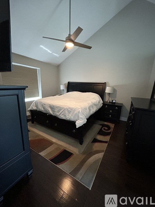 A bedroom with a bed, nightstand, and a ceiling fan.