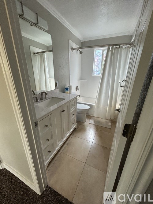 A bathroom with a toilet, sink, and mirror.