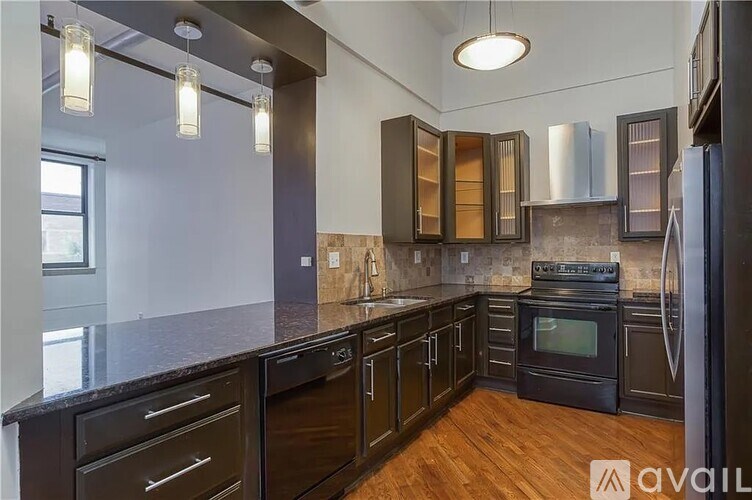 A kitchen with black cabinets and a stainless steel refrigerator.
