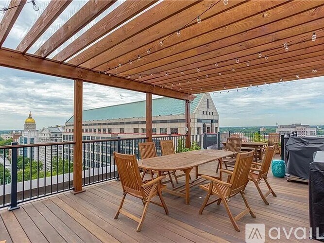 A wooden table and chairs are set up on a wooden deck with a view of the city.