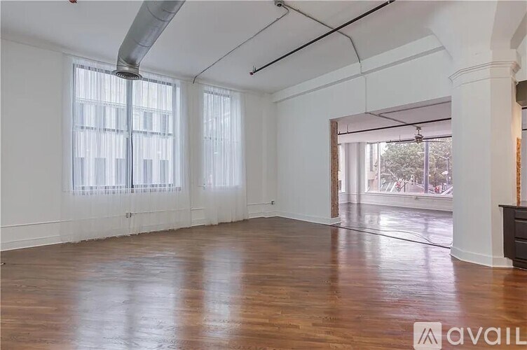A spacious room with wooden floors and white walls.