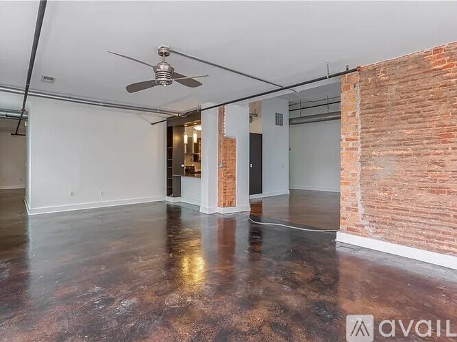 A room with a ceiling fan and brick wall.