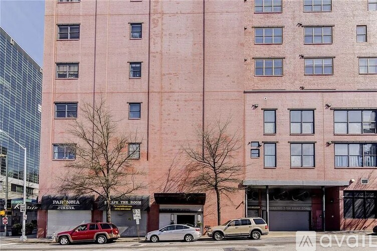 A tall pink building with a red car parked in front of it.