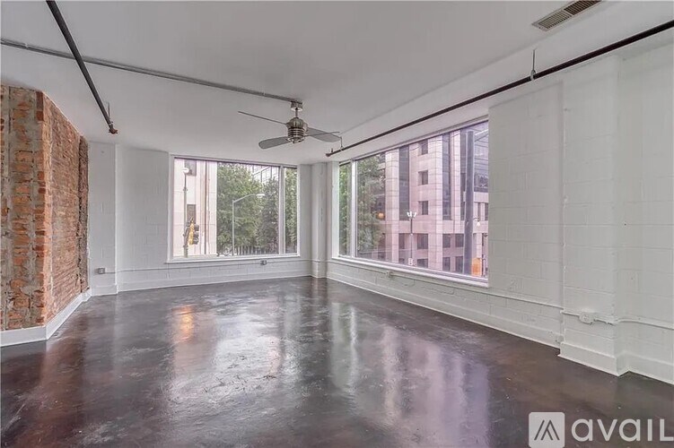 A spacious room with a ceiling fan and large windows.