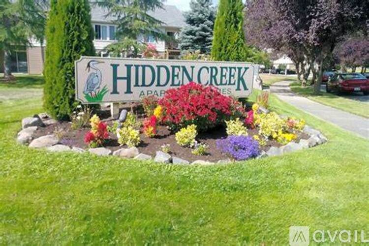 A sign for Hidden Creek Apartments is surrounded by flowers.