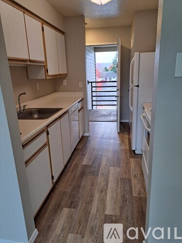 A kitchen with wooden floors and white appliances.