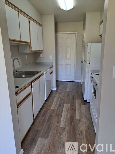 A kitchen with white cabinets and a wooden floor.