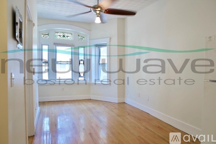 A room with a ceiling fan and a window with a view of the ocean.