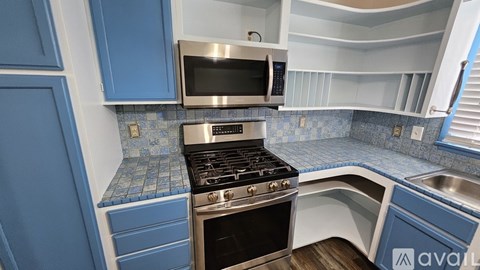 A kitchen with blue cabinets and a stove top oven.