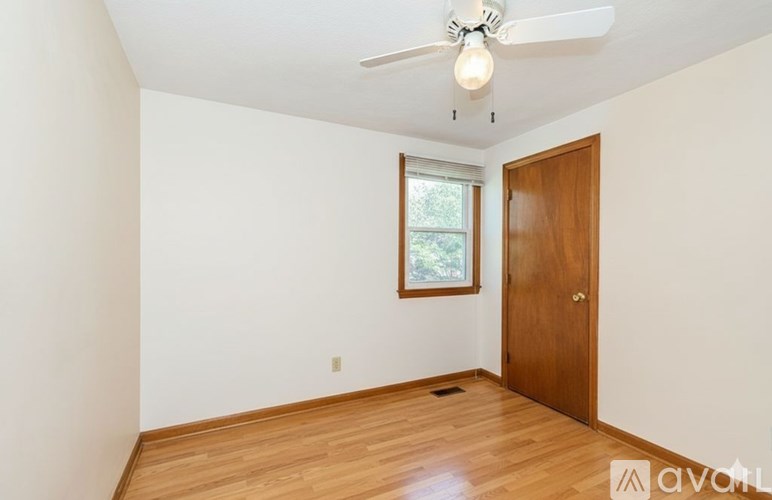 A room with a ceiling fan and a door.