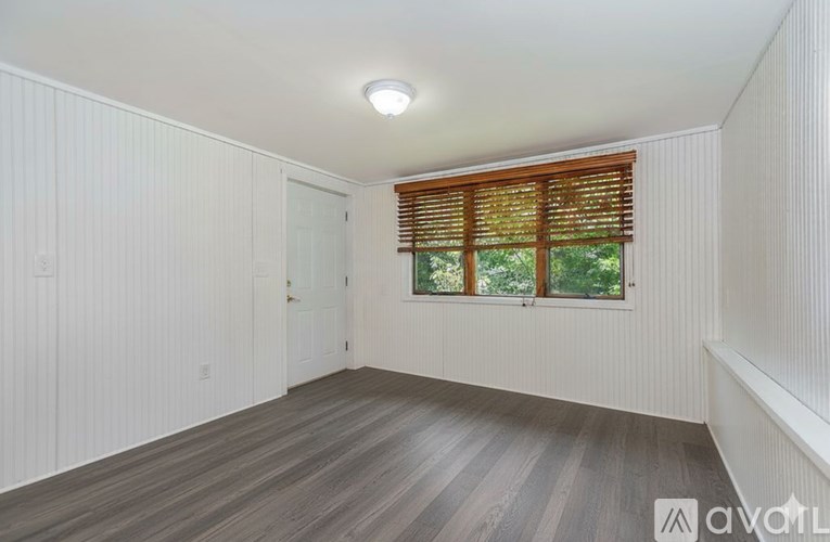 A room with wooden flooring and a window with wooden blinds.