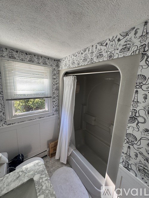 A bathroom with a patterned wallpaper and a window with blinds.