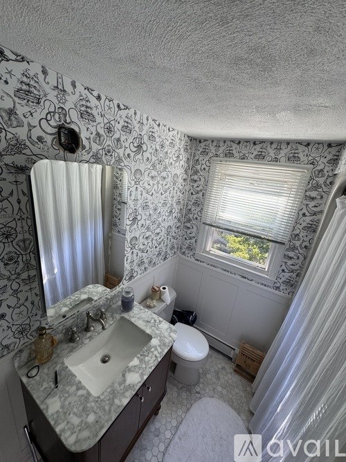 A bathroom with a marble sink and a window with blinds.