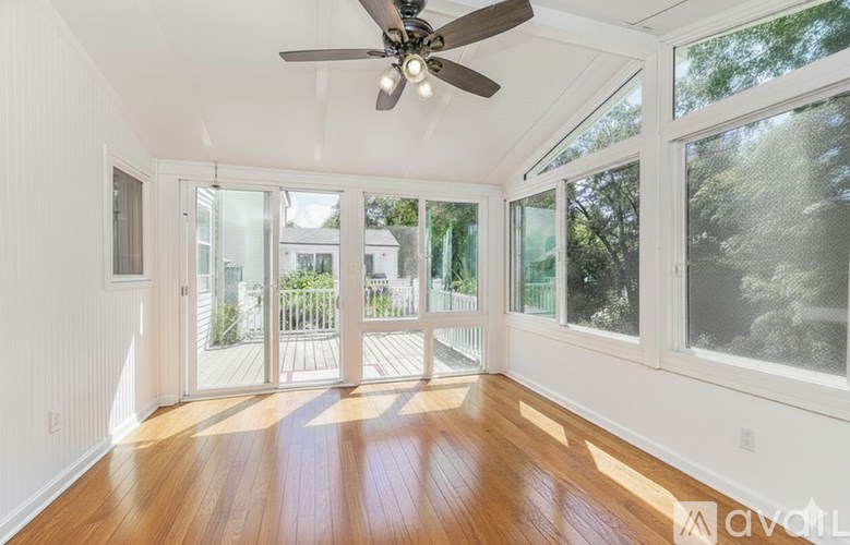 A sunny room with a ceiling fan and sliding glass doors.