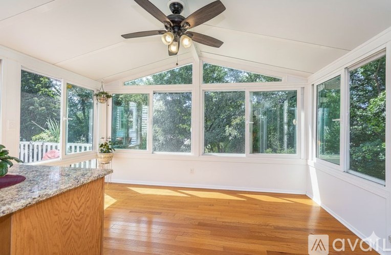 A sunny room with a ceiling fan and a counter.