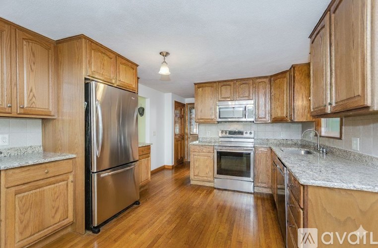 A kitchen with wooden cabinets and a stainless steel refrigerator.