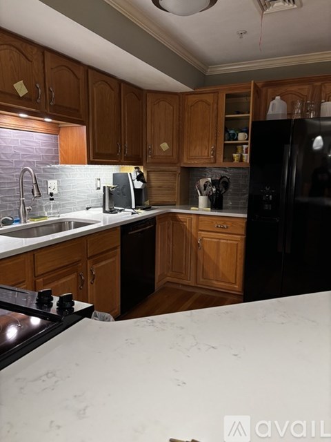 A kitchen with wooden cabinets and a black refrigerator.