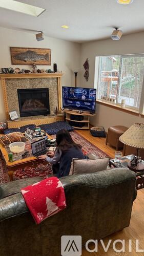 A person is sitting on a couch in a living room with a fireplace and a TV.
