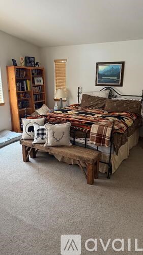 A bedroom with a bed, a bookshelf, and a painting on the wall.