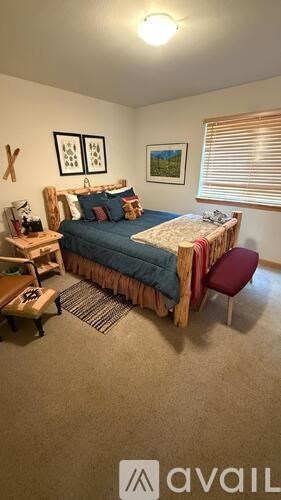 A bedroom with a bed, chair, and two pictures on the wall.