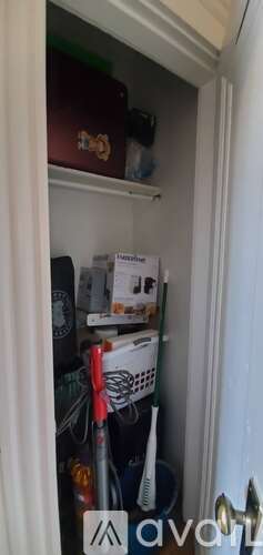 A small, dark brown box with a gold emblem is on the top shelf of a white cabinet.