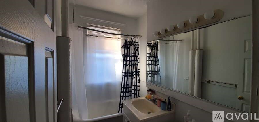 A bathroom with a sink, mirror, and shower.