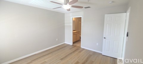 A room with a white door and a ceiling fan.