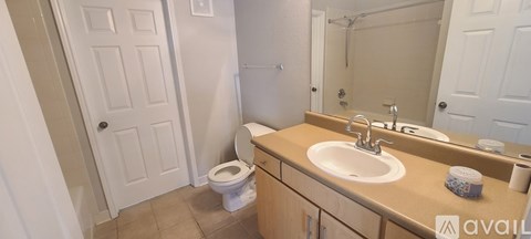 A bathroom with a toilet, sink, and mirror.