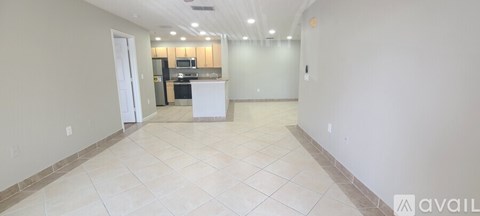 A spacious room with a kitchen in the background and a counter in the foreground.