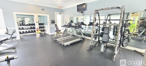 A gym with a variety of equipment including weights, treadmills, and a television.
