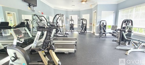 A gym with a variety of equipment including treadmills, weights, and a television.