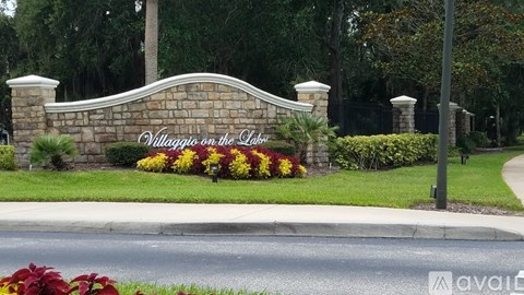 A sign that says "Villaggio on the Lake" is in front of a street.