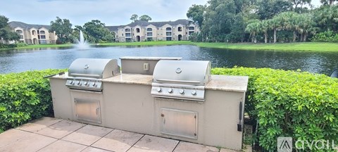 A built in BBQ grill with a view of a lake and houses in the background.