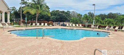 A large outdoor swimming pool surrounded by palm trees and lounge chairs.